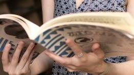 Close up of a comparative literature student holding an open book.